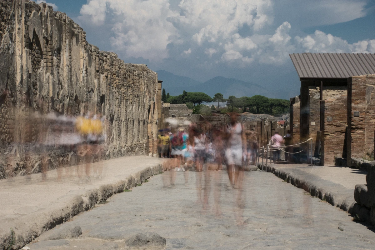 Blurred tourists walking Via dell’Abbondanza in Pompeii on a guided tour of the excavations