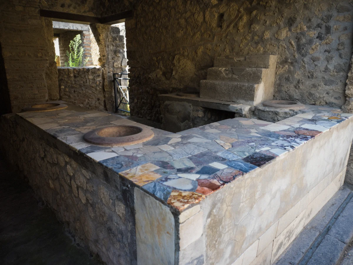 The counter of a Pompeii thermopolium explained by a guide on a private tour of Pompeii