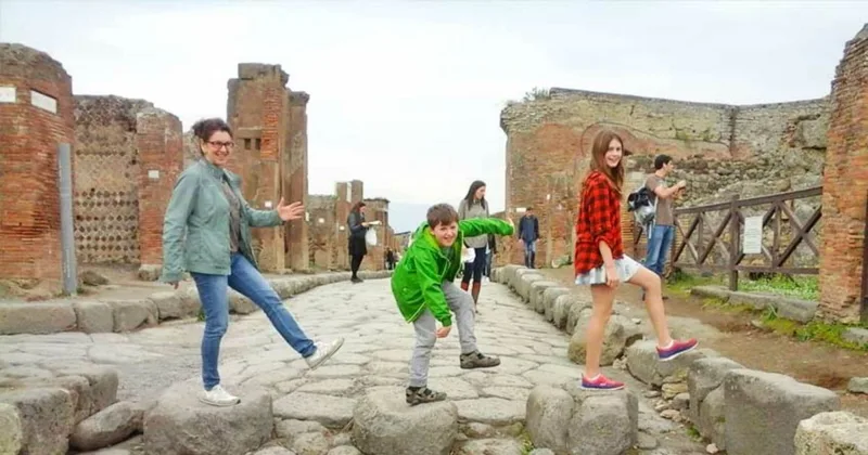 Family with children following an archaeologist guide between the stone houses of Pompeii on a private family tour